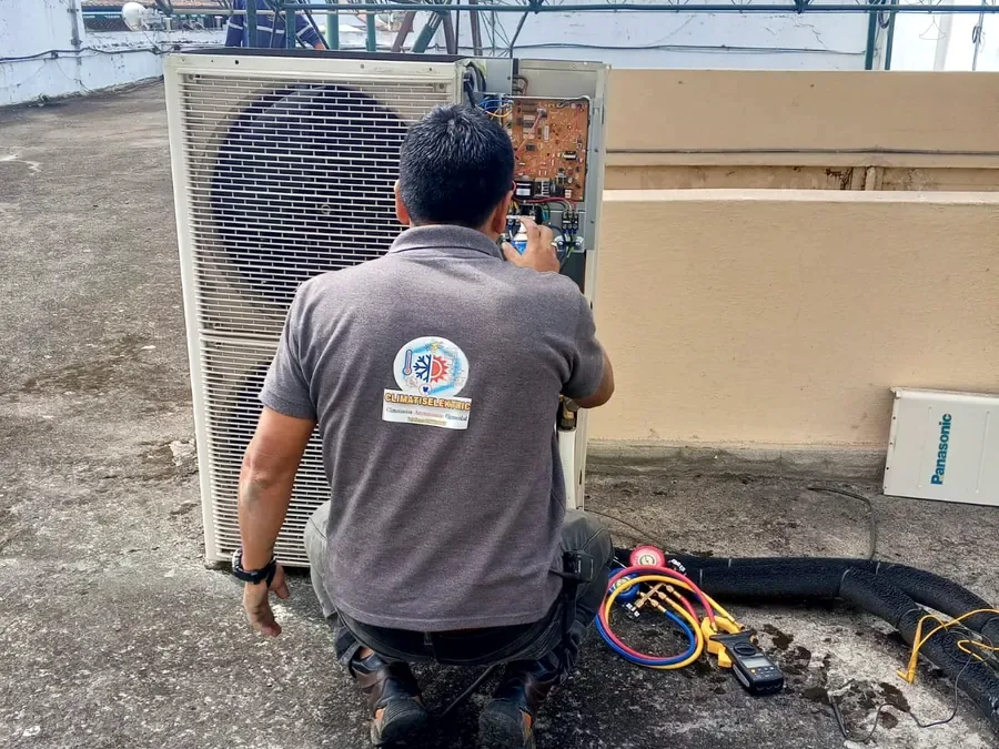 Técnico revisando la tarjeta electrónica de una unidad condensadora en una azotea